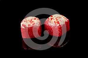 Two red tuna rolls with red caviar and shrimp on a black background with reflection. Close-up  top view. Food delivery concept
