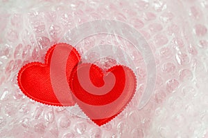 Two red valentine hearts are packed in a transparent bubble wrap. The concept of love, Valentine Day, the fragility of love.