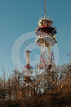 Two telecommunications towers with antennas on a clear blue sky background