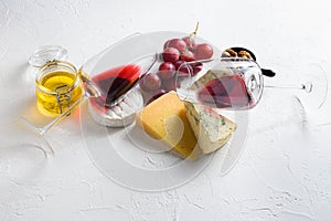 Two red wine glass with Cheese appetizer selection or whine snack set. Variety of cheese, grapes, pecan nuts side view