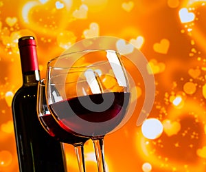 Two red wine glasses against golden hearts bokeh lights background