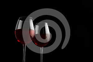 Two red wine glasses on a black background