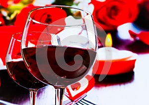 Two red wine glasses on blur hearts and roses decoration background