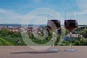 Two red wine glasses on panoramic view of fields and historic old town of Bamberg, Germany