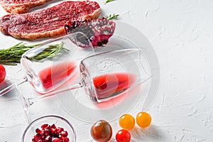 Two red wine glasses with seasonings and beef steak, over white background, side view selective focus with space for text