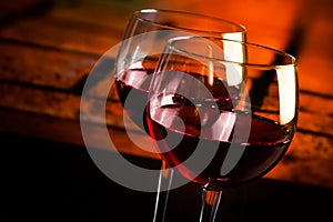 Two red wine glasses on wood table with warm atmosphere background