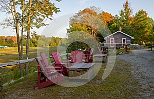 Two red wooden muskoka chairs in a park in autumn, fall season, Garden furniture. Sunny and warm fall season