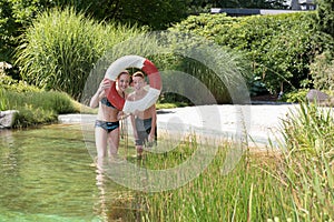 Two redhaired kids in the pool playing with a safety ring