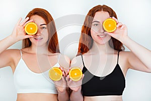 Two redheaded positive women both standing on isolated white backgroung closing eye with one half of orange holding another half