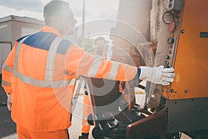 Two refuse collection workers loading garbage into waste truck