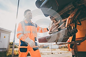 Two refuse collection workers loading garbage into waste truck