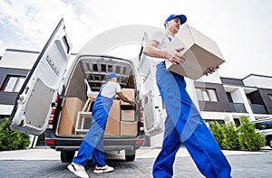 Two removal company workers unloading boxes and furniture from minibus