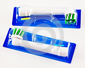 Two replacable toothrush heads in plastic containers.