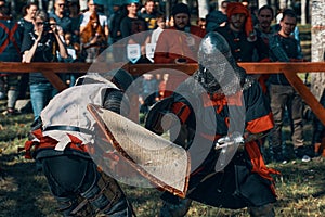 Two representatives of historical clubs in armor fight with swords.
