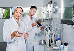 Two researchers in white coat checking wine acidity in laboratory