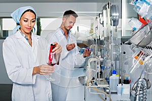 Two researchers in white coat checking wine acidity in laboratory