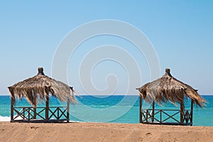 Two rest shacks on tropical beach on the shore of the ocean