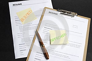 Two resume templates and sticks on it, black background. HR made decision and approved one candidate and rejected to another.Proce