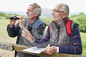 Two Retired Male Friends On Walking Holiday Looking Through Binoculars