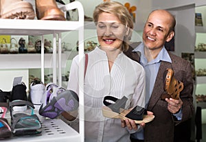 Two retirees together choosing pair of shoes in fashion store