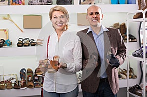 Two retirees together choosing pair of shoes in fashion store