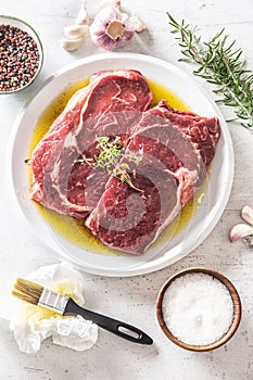 Two Rib eye steak salt spices rosemary garlic in olive oil - top of view