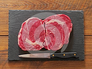 Two rib eye steaks on a slate plate. Top view.