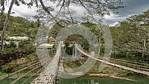 Two rickety Bamboo Hanging Bridges span over a tropical river. photo