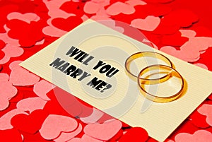 Two rings and a card with marriage proposal