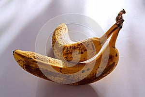 Two ripe bananas on white table against sunlights 1