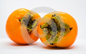 Poltava, Ukraine - 1 May, 2021: Two ripe orange persimmons Diospyros kaki on a white background photo