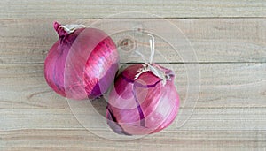 Two ripe red onions on a wooden table with copy space