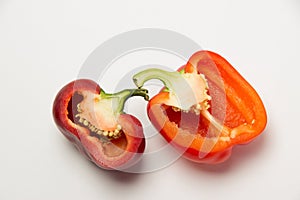 Two ripe red peppers in a cut on a white background