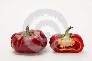 Two ripe red peppers in a cut on a white background