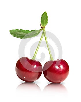 Two ripe sweet cherries with a green leaf isolated on a white background. Fresh berry fruits.