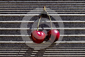 Two ripe sweet cherries with water drop on gray concrete background. Minimalistic style