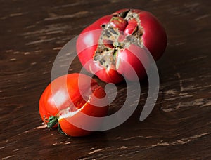 Two ripe ugly trendy tomatoes on a brown background. One tomato cracked