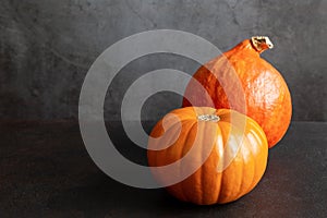 Two ripe whole orange pumpkins of different grades on black background with copy space.
