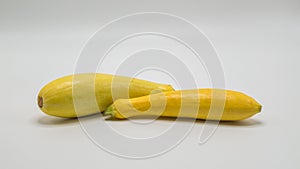 Two yellow summer squash on white