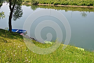 Two river boats in water, moored to the shore, river bank, with green grass coast