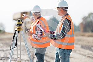 Road construction workers using measuring device on the field