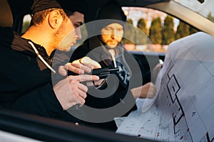 Two robbers planning and pointing on the blueprint map their objective while holding their guns