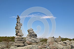 Two Rock Cairns With A Blue Sky Background.