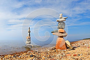 Two Rock zen pyramids of colorful pebbles on a beach on the background of the sea