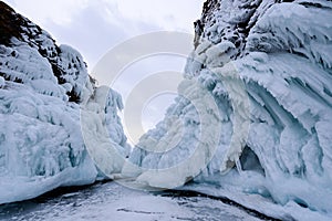 Two rocks covered with icicles. Lake Baikal in cloudy weather. Southern Cape of island Olkhon Mare`s head
