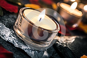 Two Romantic Candlelights On Slate With Rose Petals And Leafs