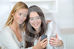 Two roommates using their smart phones on line at home