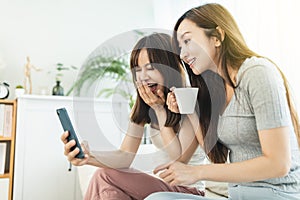 Two roommates using their smart phones  sitting on a sofa  at home photo