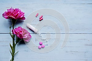 Two roses and pills with tampon on the table