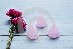 Two roses with three menstrual cups on table